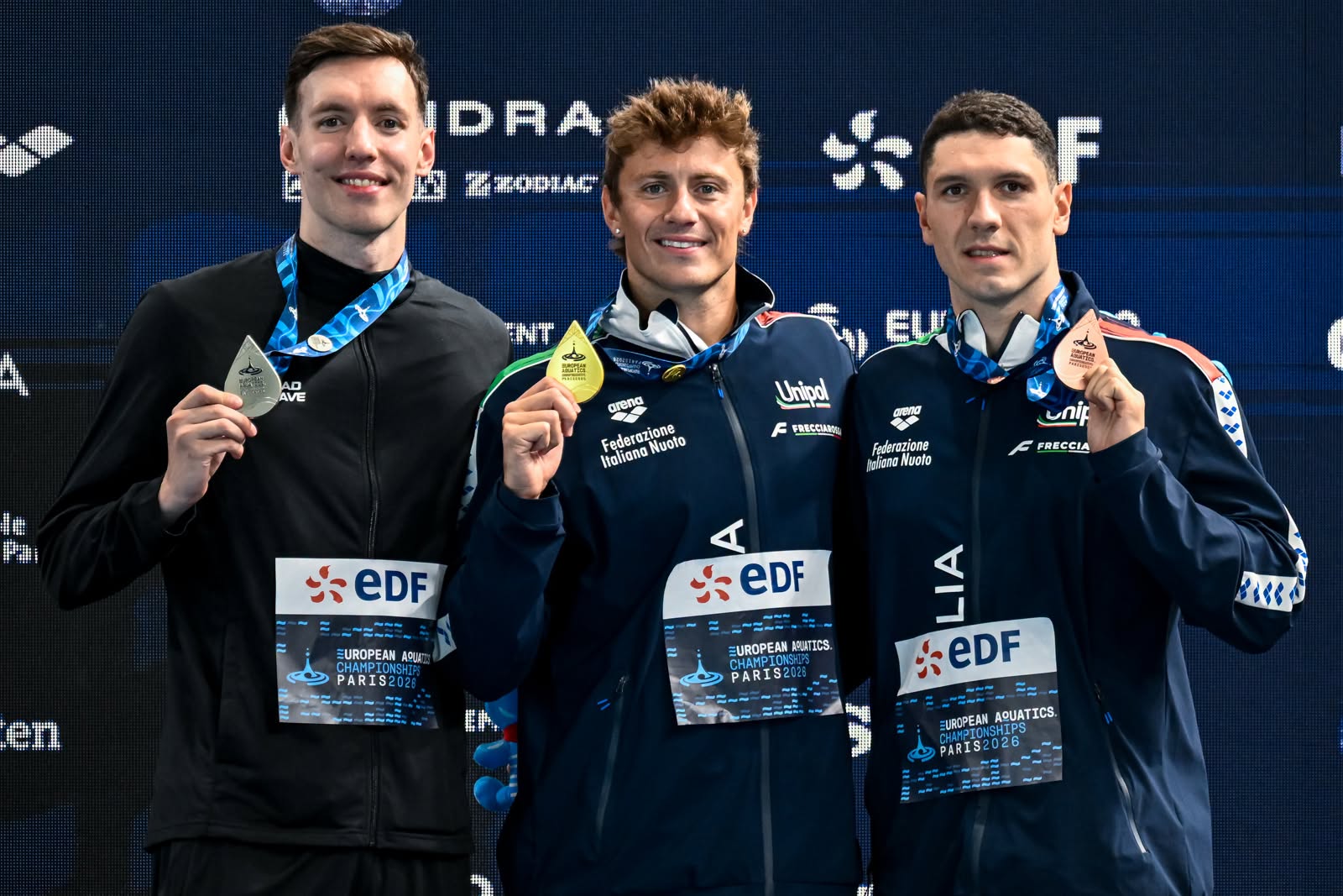 Il podio dei 100m rana a Parigi 2026. Da sinistra: IvanKozhakin, Russia, argento; Nicolò Martinenghi, Italia, oro; Simone Cerasuolo, Italia, bronzo ©FIN